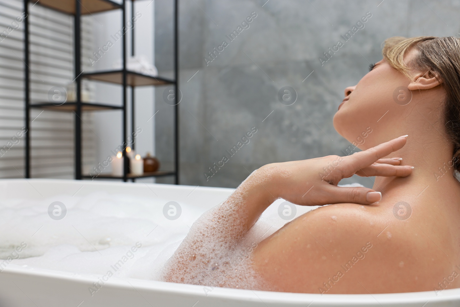 Photo of Beautiful woman taking bath with foam in tub indoors. Space for text