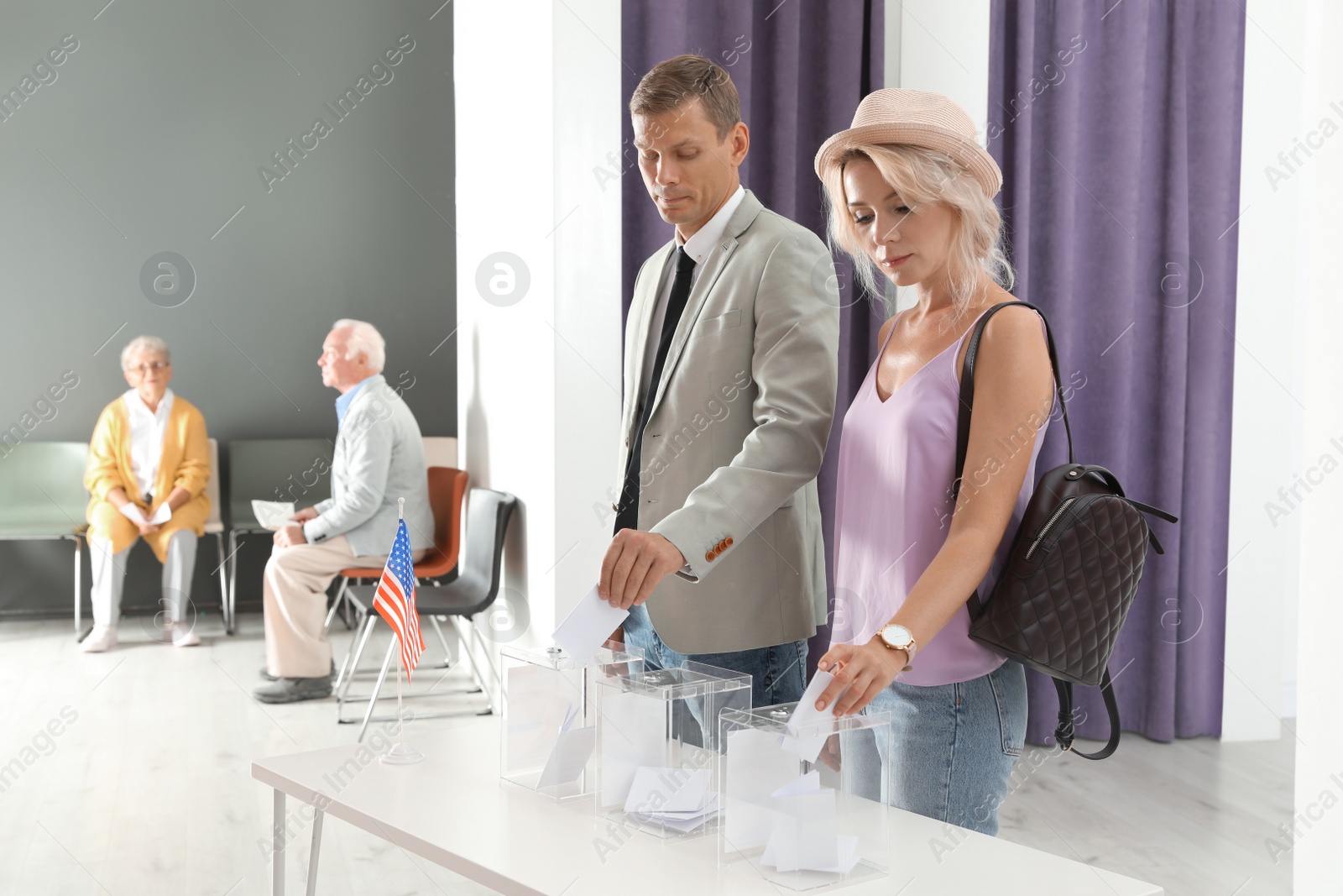 Photo of People putting ballot papers into boxes at polling station