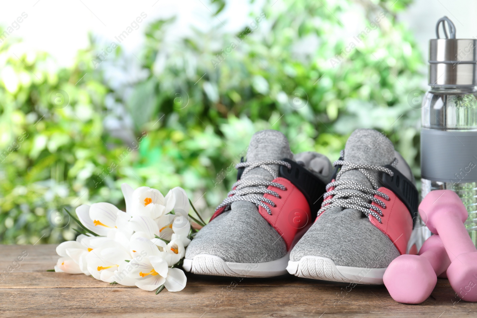 Photo of Composition with spring flowers and sports items on wooden table against blurred greenery