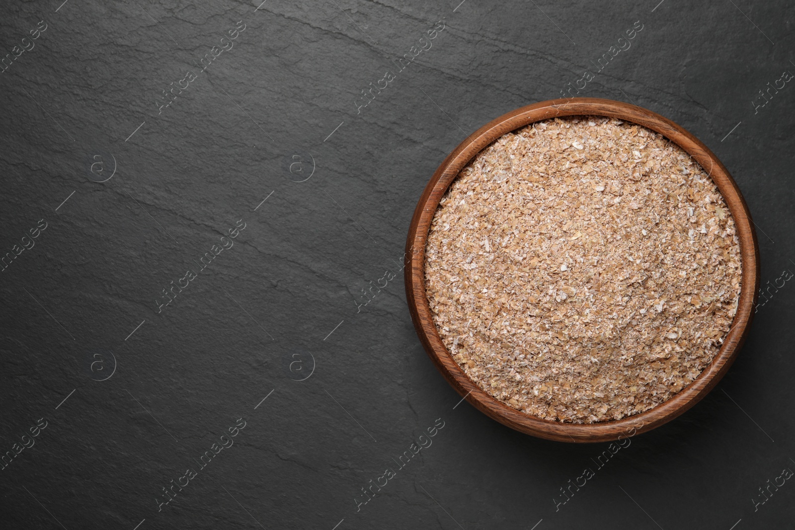 Photo of Wheat bran on black table, top view. Space for text