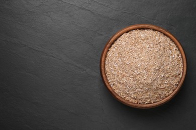 Photo of Wheat bran on black table, top view. Space for text