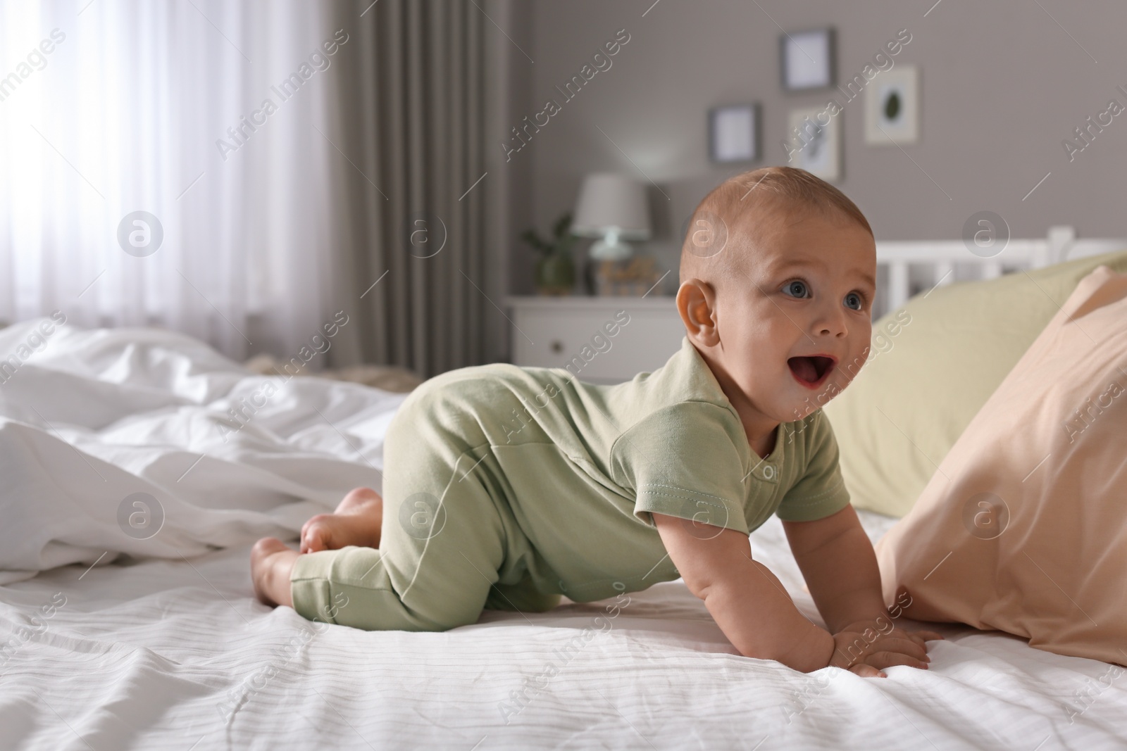 Photo of Cute baby crawling on bed at home