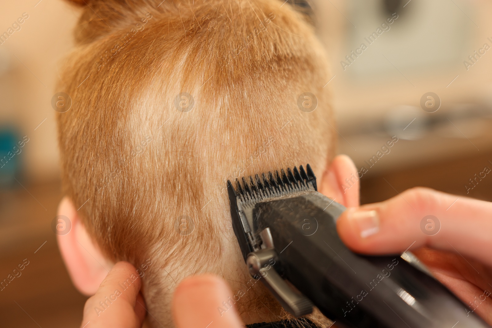 Photo of Professional hairdresser cutting boy's hair in beauty salon, closeup