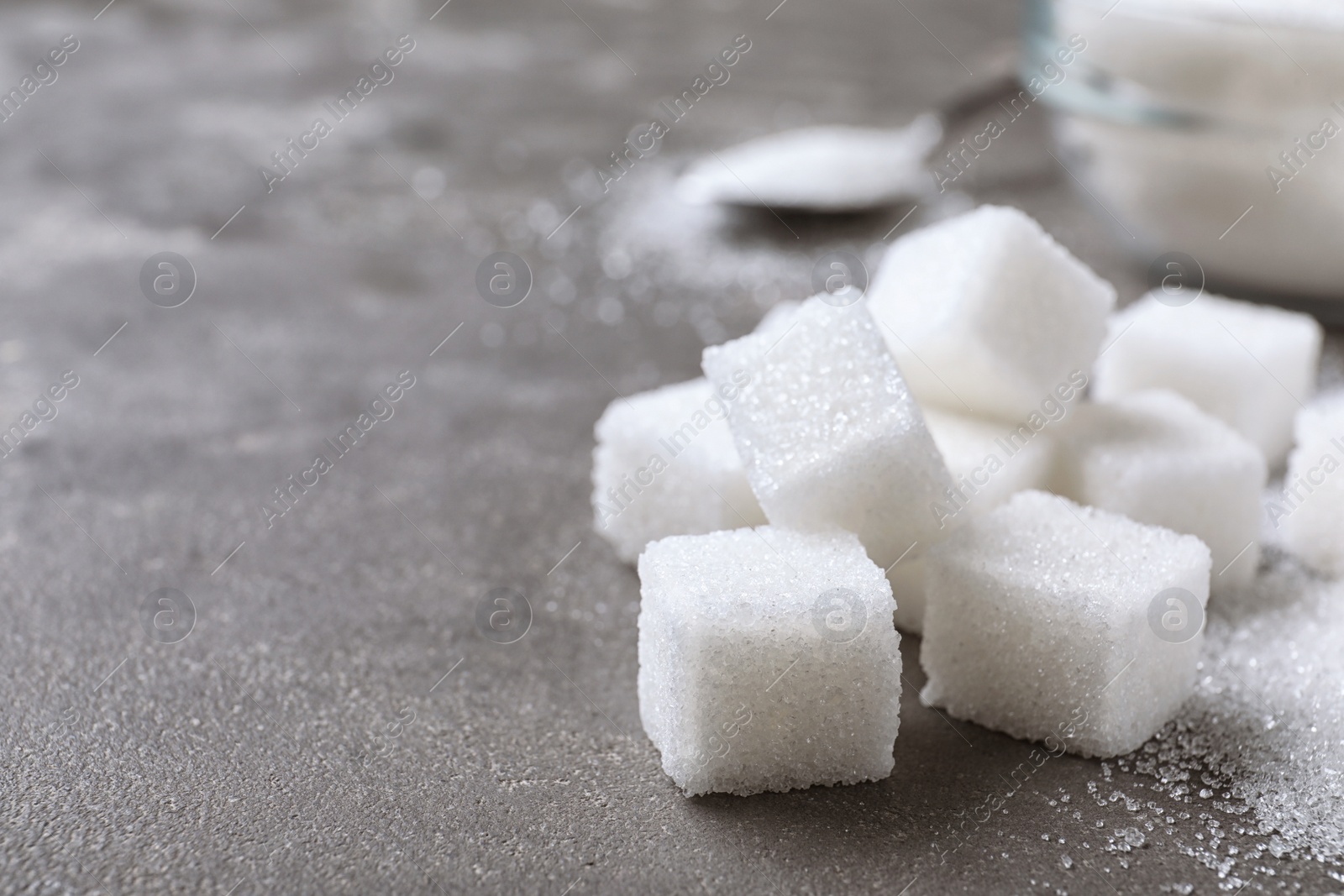 Photo of Refined sugar cubes on grey table, closeup. Space for text
