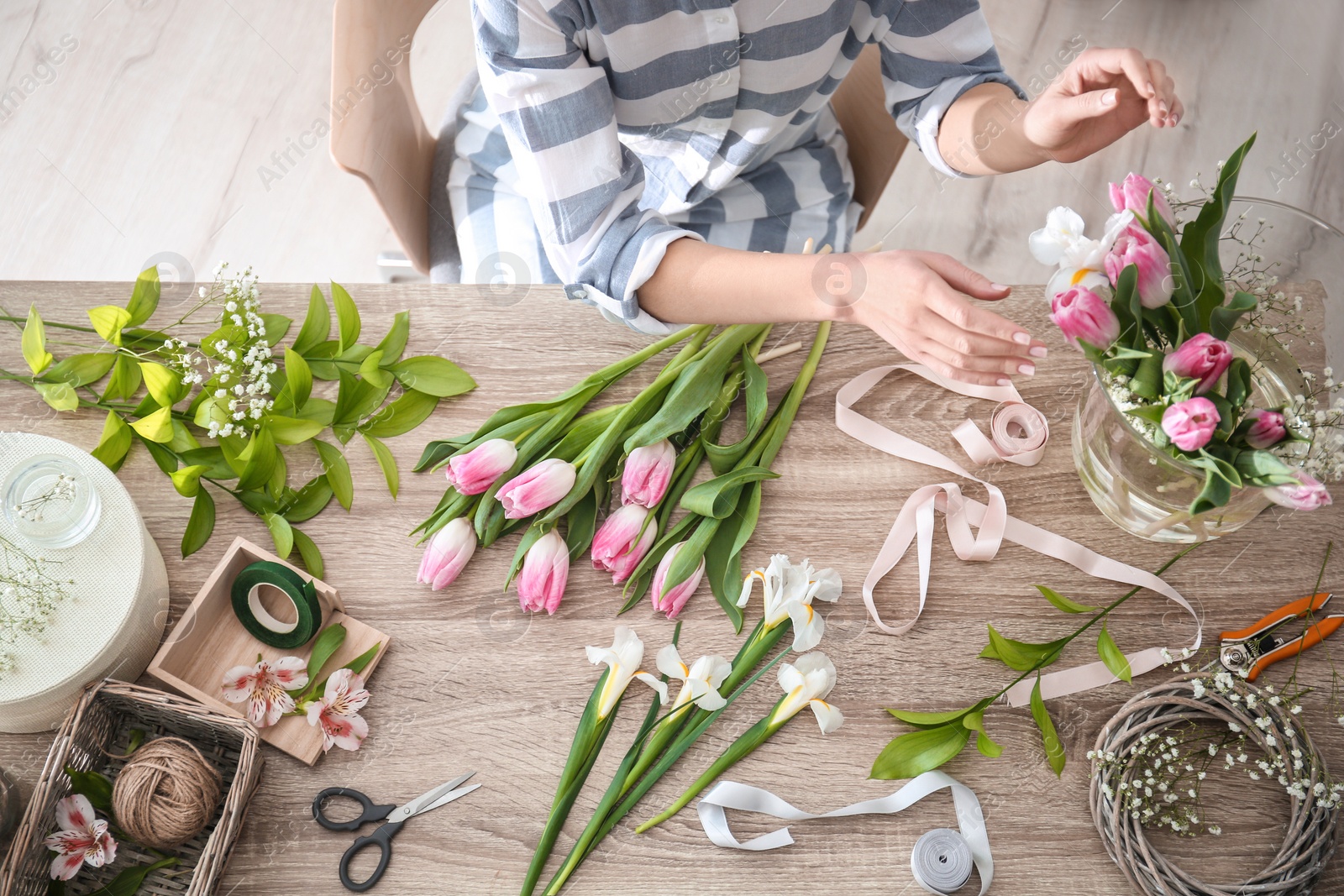 Photo of Female decorator creating beautiful bouquet at table