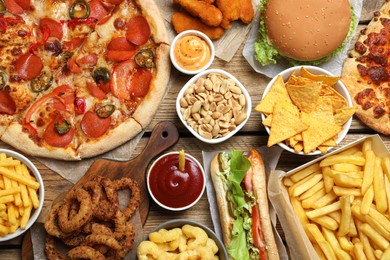 Pizza, french fries and other fast food on wooden table, flat lay