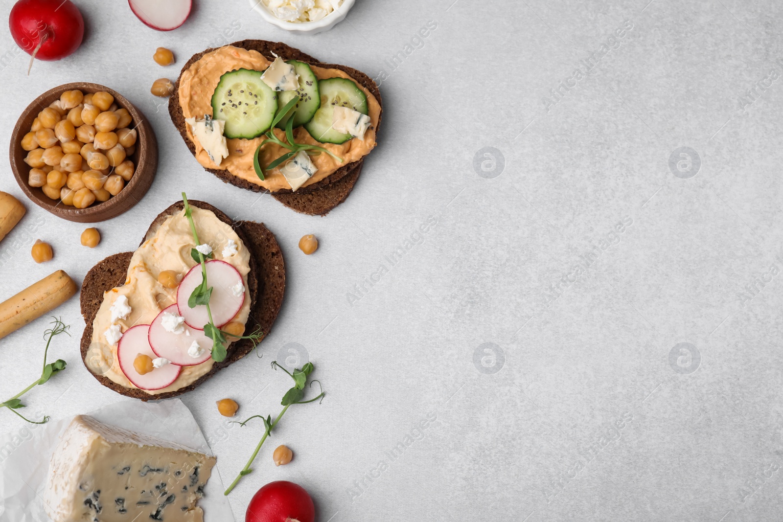 Photo of Delicious sandwiches with hummus and different ingredients on light grey background, flat lay. Space for text
