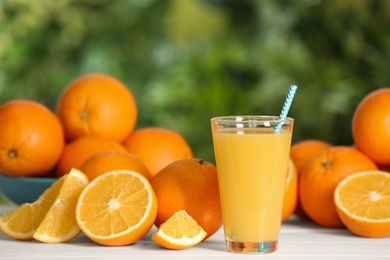 Delicious orange juice and fresh fruits on wooden table against blurred background