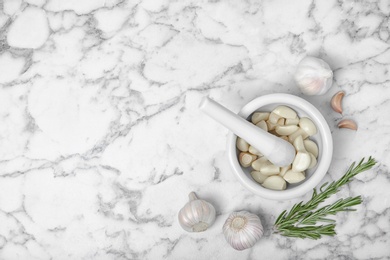 Flat lay composition with garlic and mortar on marble background