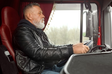 Photo of Mature driver sitting in cab of modern truck