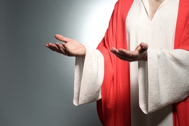 Photo of Jesus Christ reaching out his hands on grey background, closeup