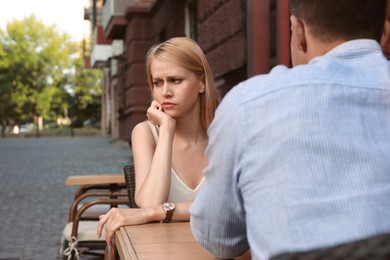 Photo of Young woman having boring date with man in outdoor cafe
