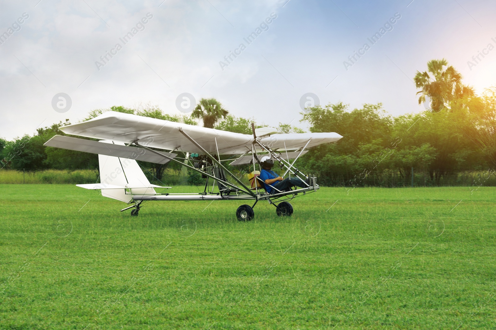 Photo of Man in light aircraft on green grass outdoors