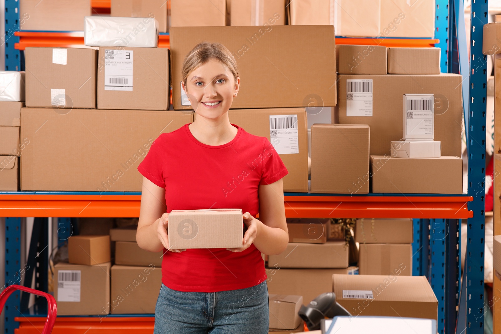 Photo of Post office worker with parcel near rack indoors