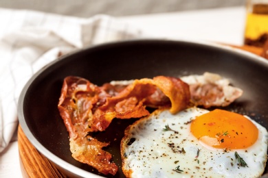 Photo of Frying pan with fried egg and bacon, closeup