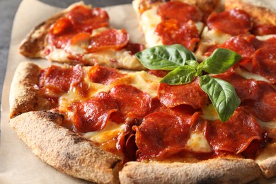 Tasty pepperoni pizza with basil on table, closeup