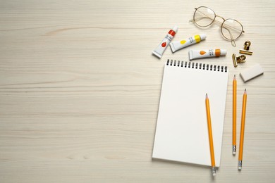 Flat lay composition with blank sketchbook on white wooden table. Space for text