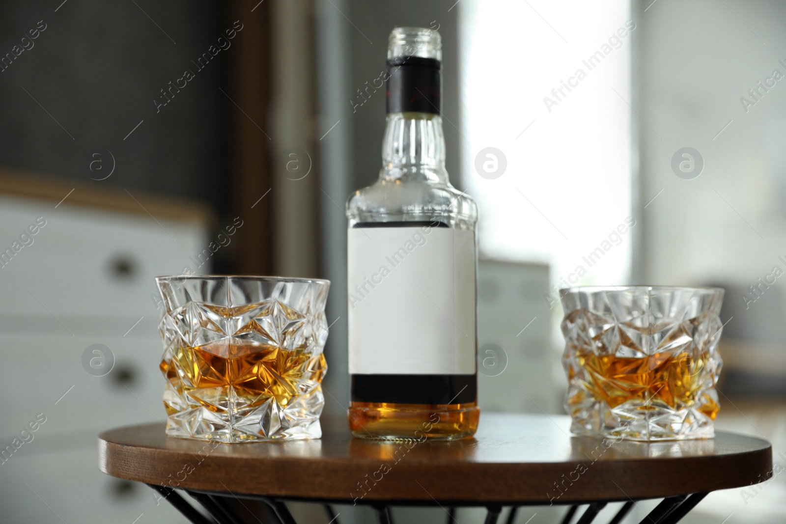 Photo of Glasses and bottle of whiskey on table indoors