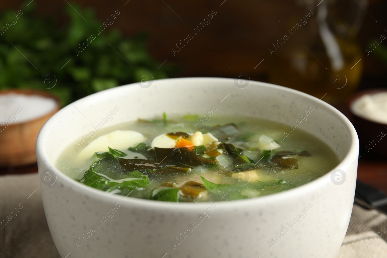 Photo of Delicious sorrel soup in white ceramic bowl, closeup