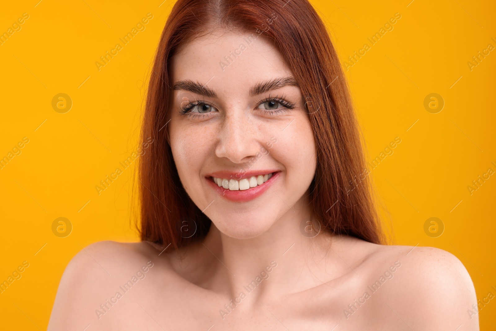 Photo of Portrait of smiling woman with freckles on yellow background