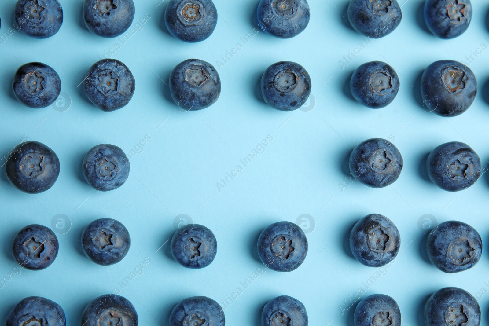 Photo of Frame of ripe blueberries on blue background, flat lay with space for text