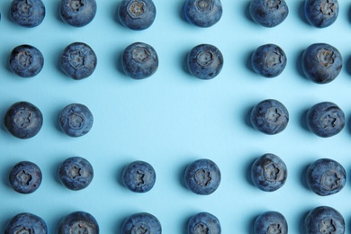 Photo of Frame of ripe blueberries on blue background, flat lay with space for text