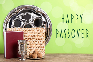 Symbolic Pesach (Passover Seder) items on wooden table against green background
