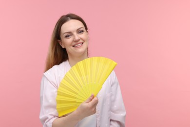 Photo of Happy woman with yellow hand fan on pink background, space for text