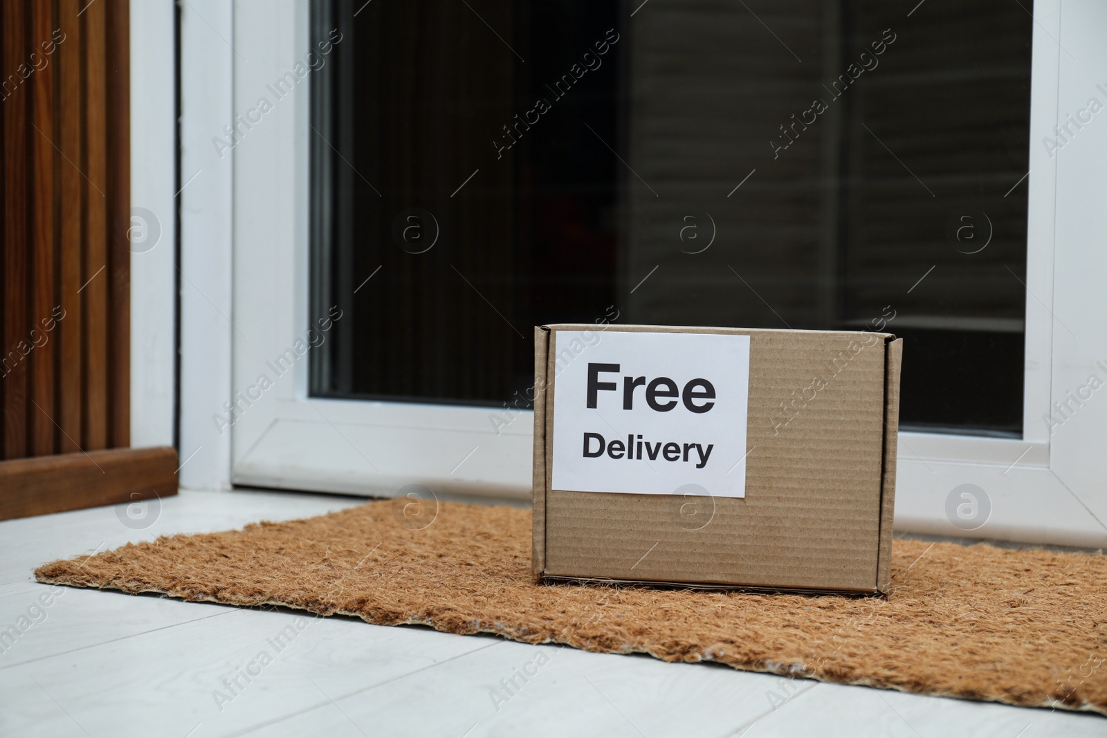 Photo of Parcel with sticker Free Delivery on rug indoors. Courier service