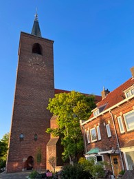 Photo of Beautiful old tower and house against blue sky, low angle view