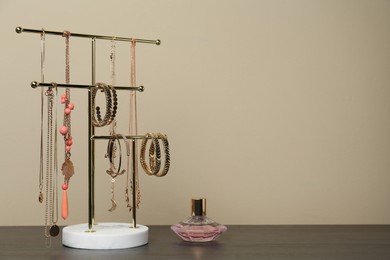 Interior element. Holder with set of luxurious jewelry and perfume on wooden table. Space for text