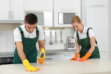 Team of janitors cleaning table in kitchen