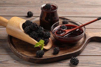Photo of Tasty blackberry jam and fresh berries on wooden table