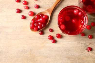 Photo of Tasty cranberry juice in glasses and fresh berries on wooden table, flat lay. Space for text