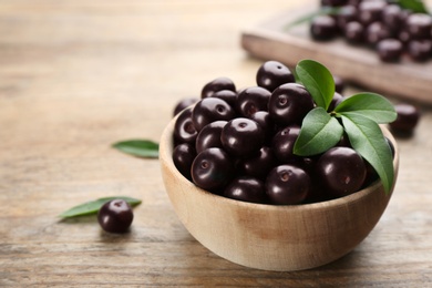 Tasty acai berries in bowl on wooden table, closeup