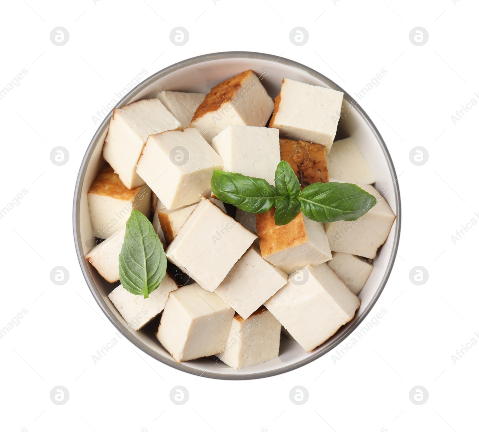 Photo of Bowl of delicious smoked tofu cubes with basil isolated on white, top view