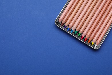 Photo of Colorful pastel pencils in box on blue background, top view with space for text. Drawing supplies