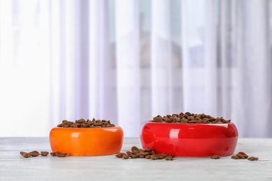 Photo of Bowls with food for cat and dog on floor. Pet care