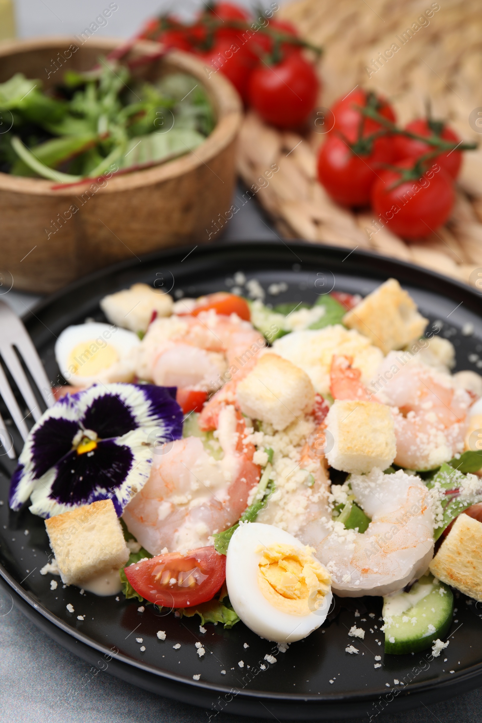 Photo of Delicious Caesar salad with shrimps served on grey table, closeup