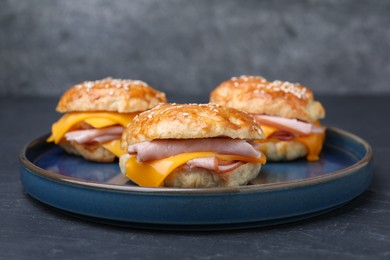 Photo of Delicious bagels with ham and cheese on black table, closeup