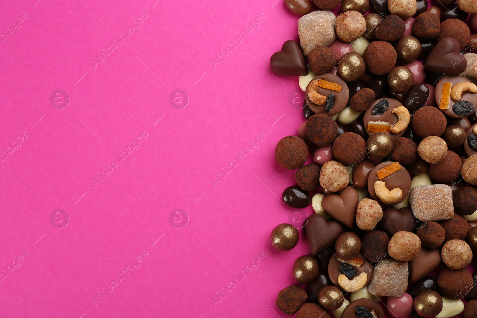 Photo of Different delicious chocolate candies on pink background, flat lay. Space for text