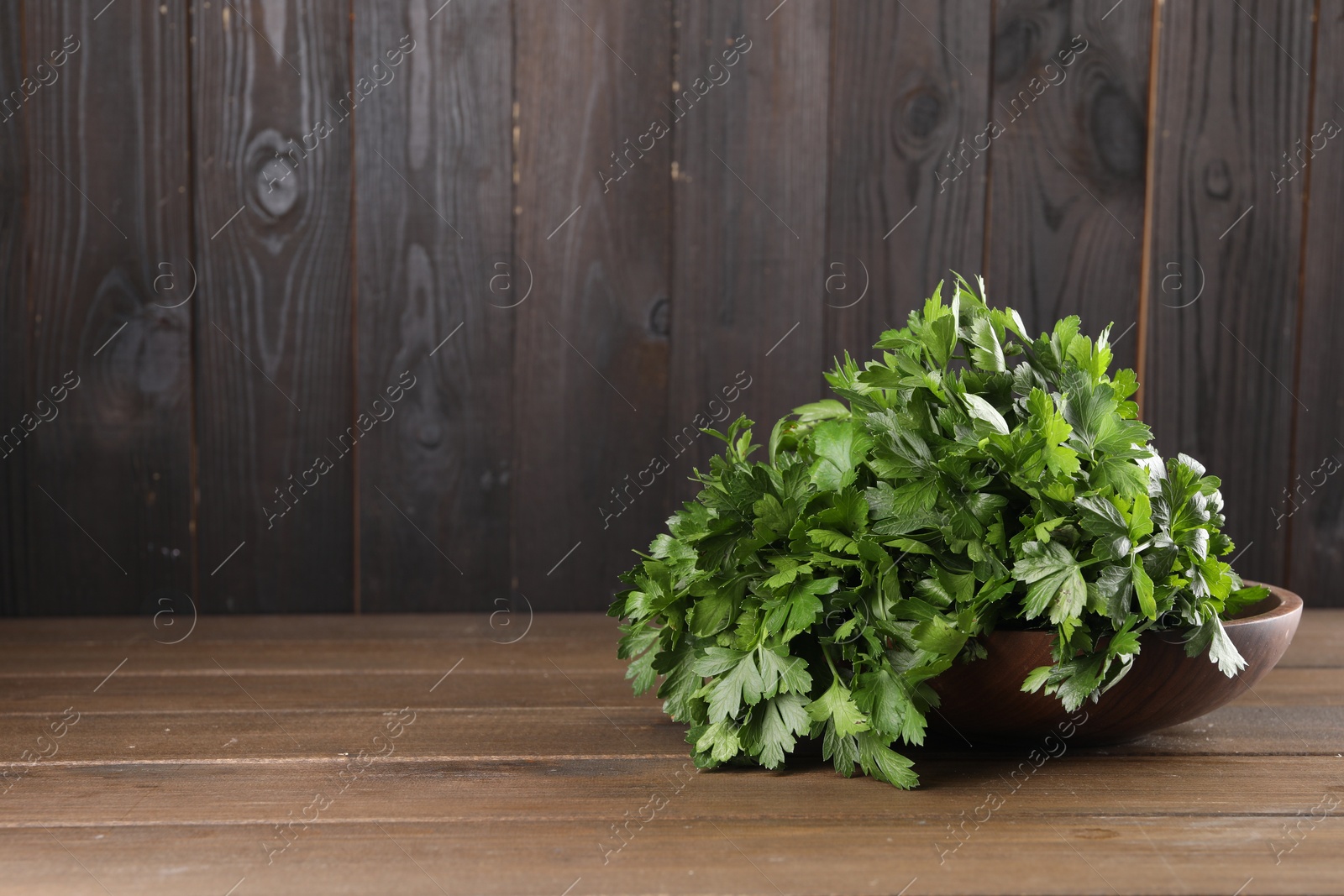 Photo of Bunch of fresh parsley on wooden table, space for text
