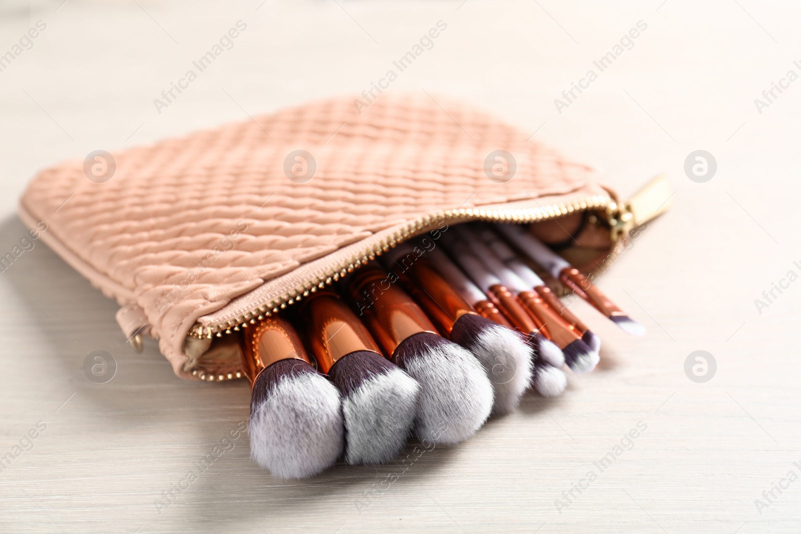 Photo of Cosmetic bag with makeup brushes on table