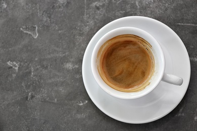 Cup of fresh aromatic coffee on grey background, top view