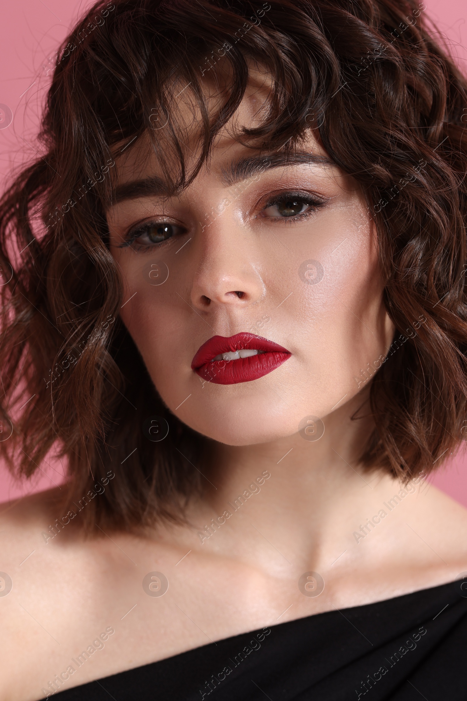 Photo of Portrait of beautiful young woman with wavy hairstyle on pink background