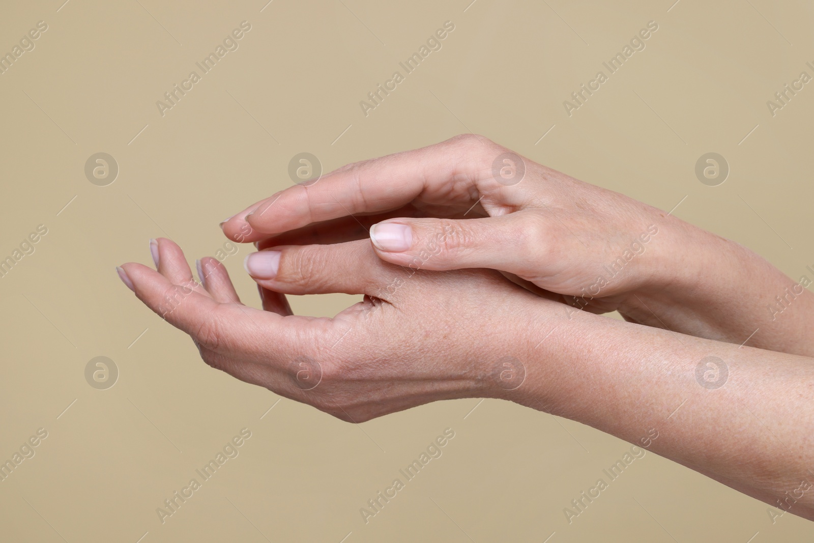 Photo of Closeup of woman's hands with aging skin on beige background. Rejuvenation treatment