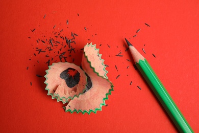 Photo of Pencil and shavings on red background, above view