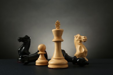 Photo of Different wooden chess pieces on dark background