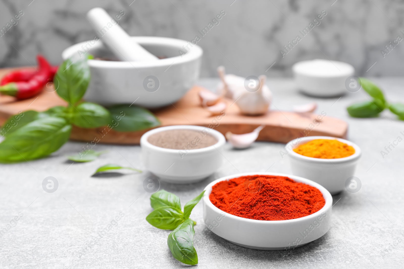 Photo of Bowls with different spices grinded in mortar on light grey table, space for text