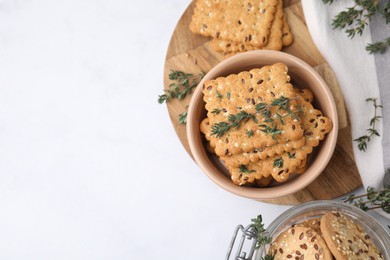 Photo of Cereal crackers with flax, sesame seeds and thyme in bowl on white table, top view. Space for text